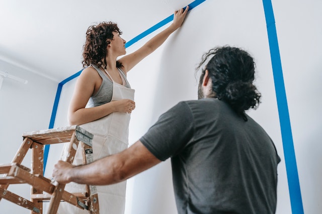 A%20person%20standing%20on%20a%20ladder%20painting%20a%20wall%20while%20another%20person%20holds%20it A%20person%20standing%20on%20a%20ladder%20painting%20a%20wall%20while%20another%20person%20holds%20it